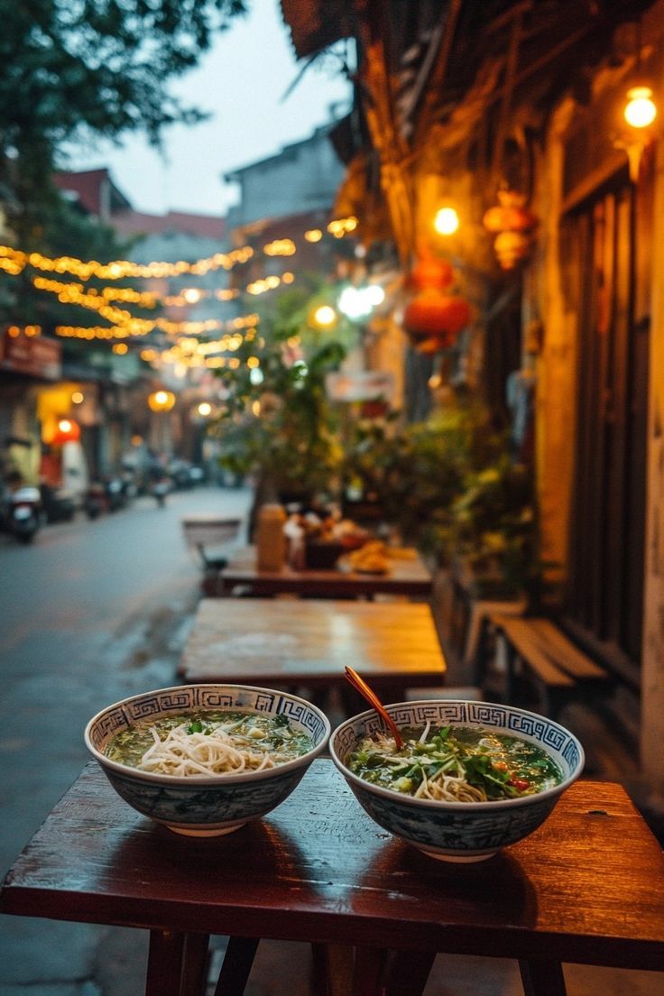 two bowls of food sit on a wooden table in the middle of an alleyway