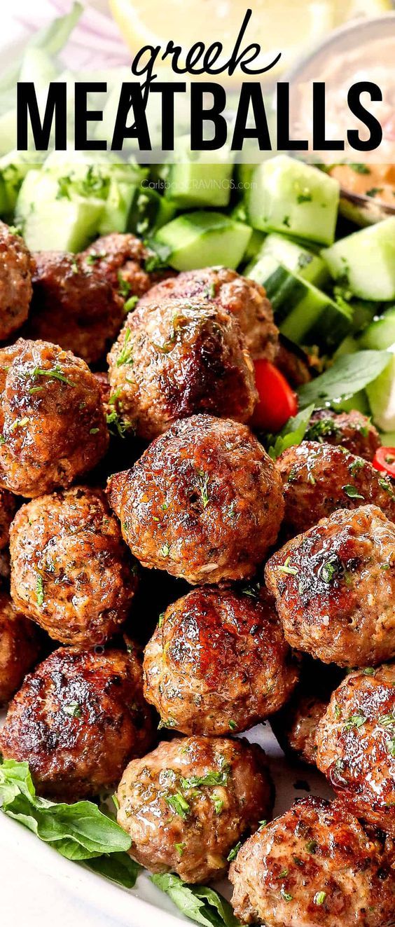 meatballs with cucumbers and tomatoes on a white platter that says greek meatballs