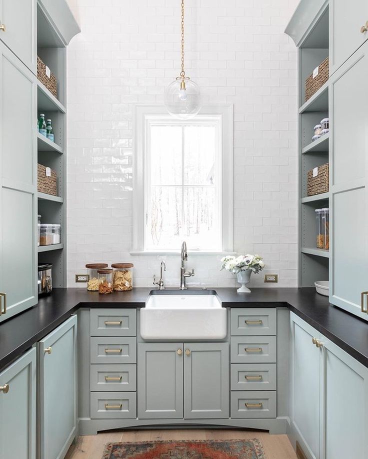 a kitchen with gray cabinets and black counter tops, white walls and an area rug on the floor