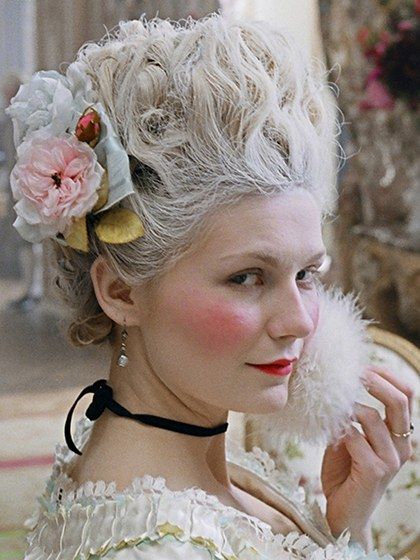 a woman with flowers in her hair sitting on a chair