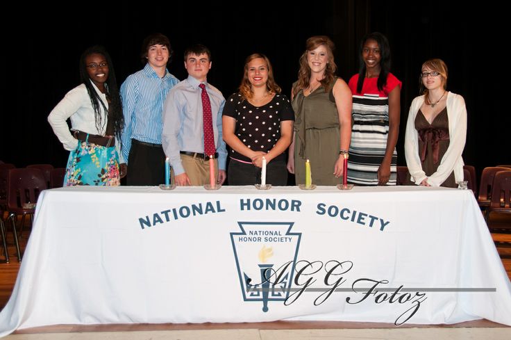 a group of people standing in front of a table with candles on it that says national honor society