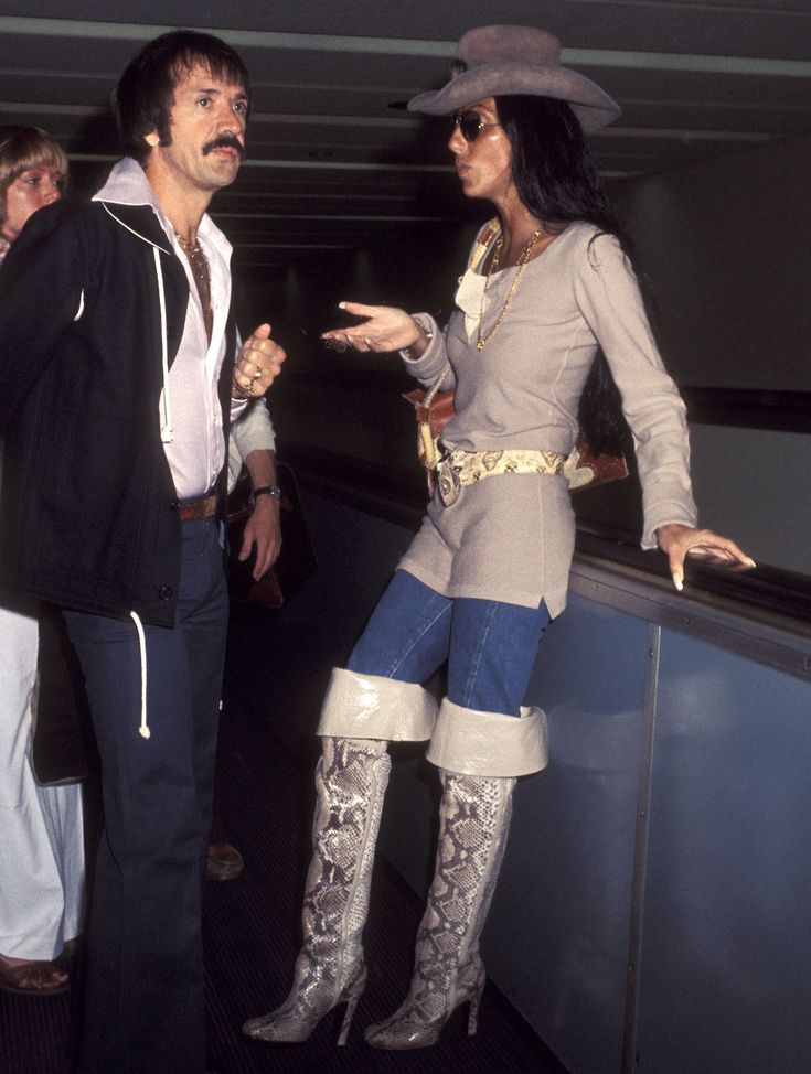 two people standing next to each other near an escalator and one person pointing at something