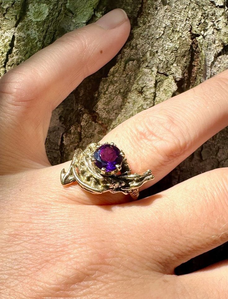 This solid 14k gold detailed dragon wraps gracefully around a sparkling, 7mm Amethyst gemstone. Here the ring is pictured with an Amethyst  but other gemstone choices are available.  Please select your desired gemstone in the dropdown options menu. You may choose between a Blue Topaz, Citrine, Amethyst, or Mozambique Garnet, Rhodolite Garnet,  Peridot, Onyx or Rainbow Moonstone. We have many ring size and gemstone combinations immediately available but not all possible variations. If we need to custom make this piece for you, please allow us a 2-4 weeks for creation. We will contact you to let you know availability. All Marty Magic Jewelry is packaged in a beautiful ring box embossed with the gold foil Marty Magic dragon logo. Perfect for any occasion! Designed in Santa Cruz, California by Unique Gold Amethyst Ring, Unique Purple Amethyst Ring With Accent Stones, Unique Yellow Gold Amethyst Ring, Unique Yellow Gold Amethyst Ring For Anniversary, Unique Purple Jewelry With Accent Stones, Purple Amethyst Fantasy Jewelry, Fantasy Style Amethyst Purple Jewelry, Fantasy Style Purple Amethyst Jewelry, Unique Purple Amethyst Ring For Wedding