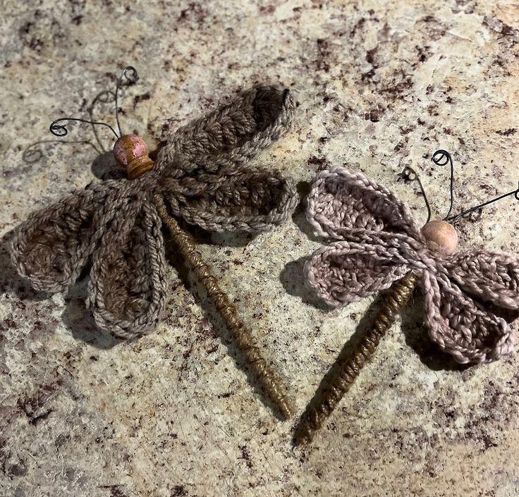 two crocheted butterflies sitting on top of a stone