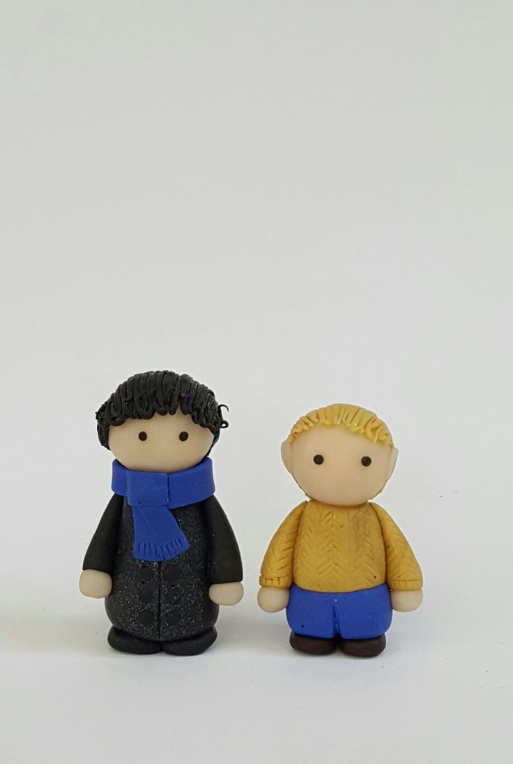 two small figurines sitting next to each other on a white surface, one is wearing a blue scarf