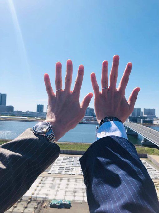 a man in a suit and tie is holding his hands up to the sky over a body of water