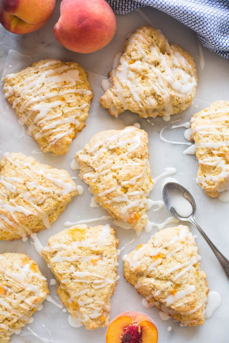 peach scones with icing and fresh peaches next to them on a plate