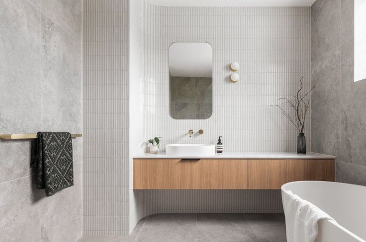 a bathroom with a sink, mirror and bathtub next to a wall mounted towel rack