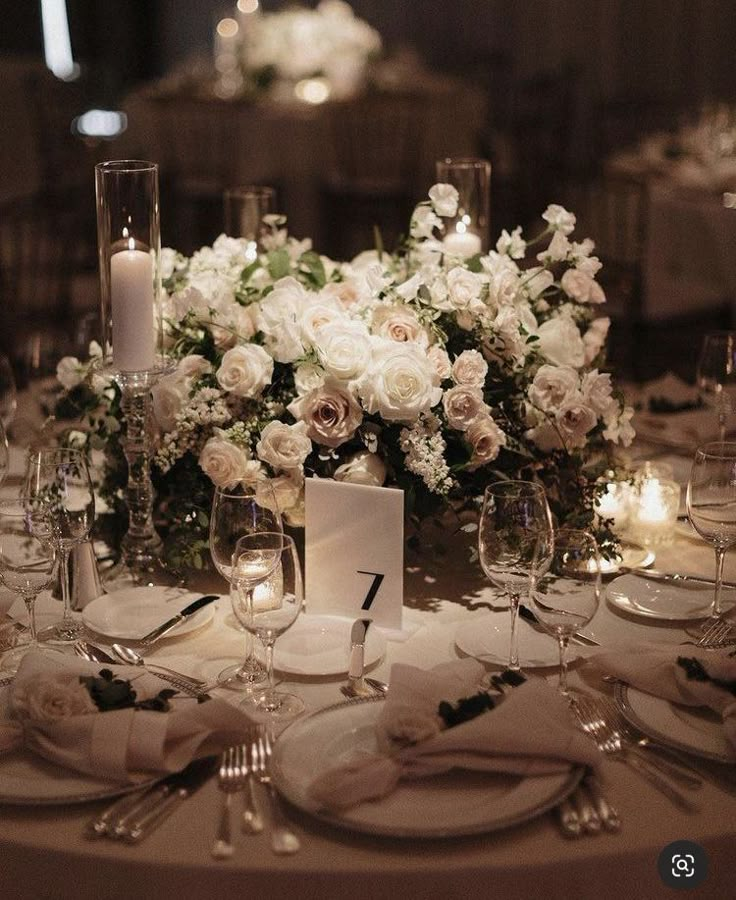 the table is set with white flowers and candles for an elegant wedding reception or special event