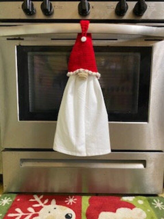 a towel hanging on the oven door knobs in front of an oven with christmas decorations