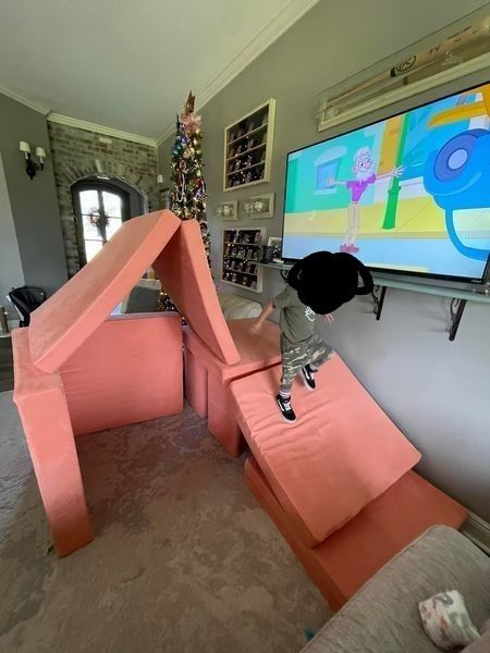 a young boy is playing on a large screen tv in the living room with pink couches