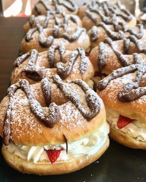 some very tasty looking pastries with frosting and strawberries on them sitting on a table