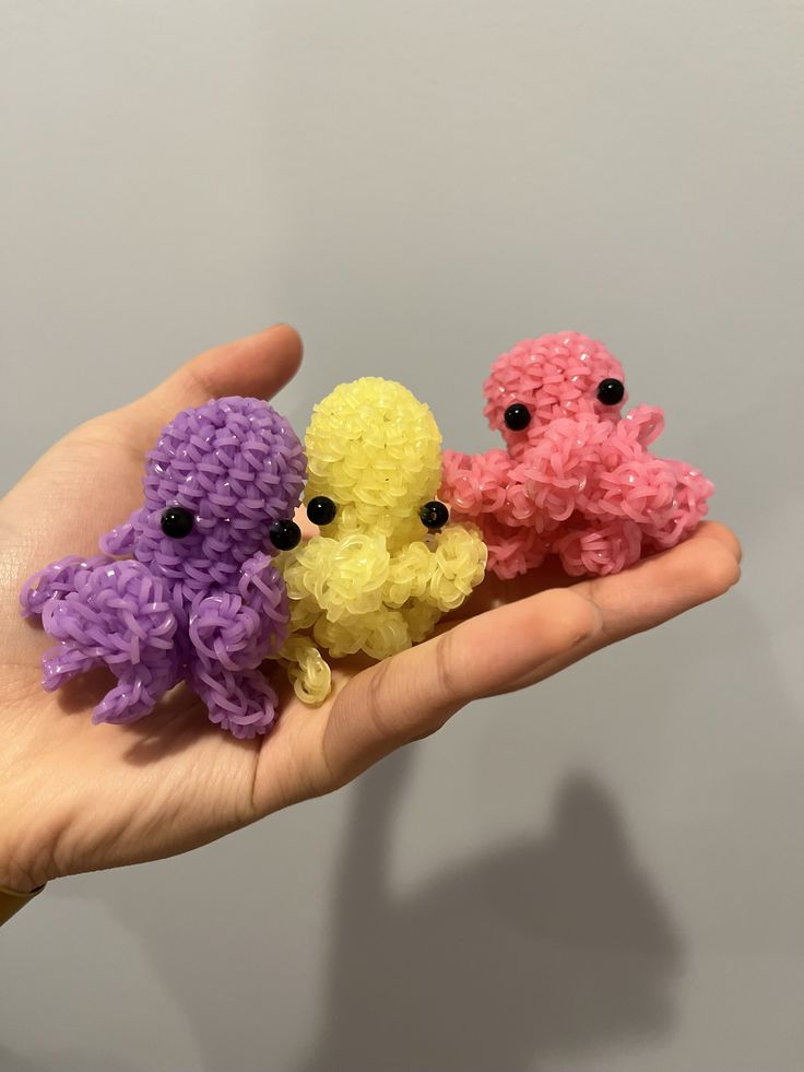 three small crocheted animals sitting on top of each other in someone's hand