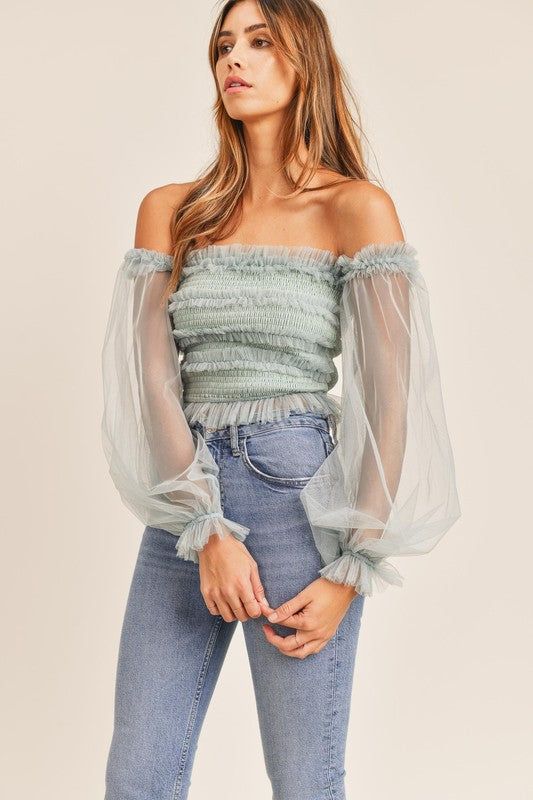 This stunning top features a sheer sleeve, smocked bodice with ruffle detail and off-the-shoulder silhouette. Pair with our Kan Can High Rise Skinny Jeans for a trendy look. Tulle Top, Tulle Sleeves, Off Shoulder Tops, Sheer Sleeves, Ruffle Top, Cute Tops, Smocking, Off The Shoulder, Bodice