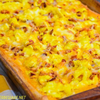 a casserole dish with cheese and other toppings in a wooden pan on a table