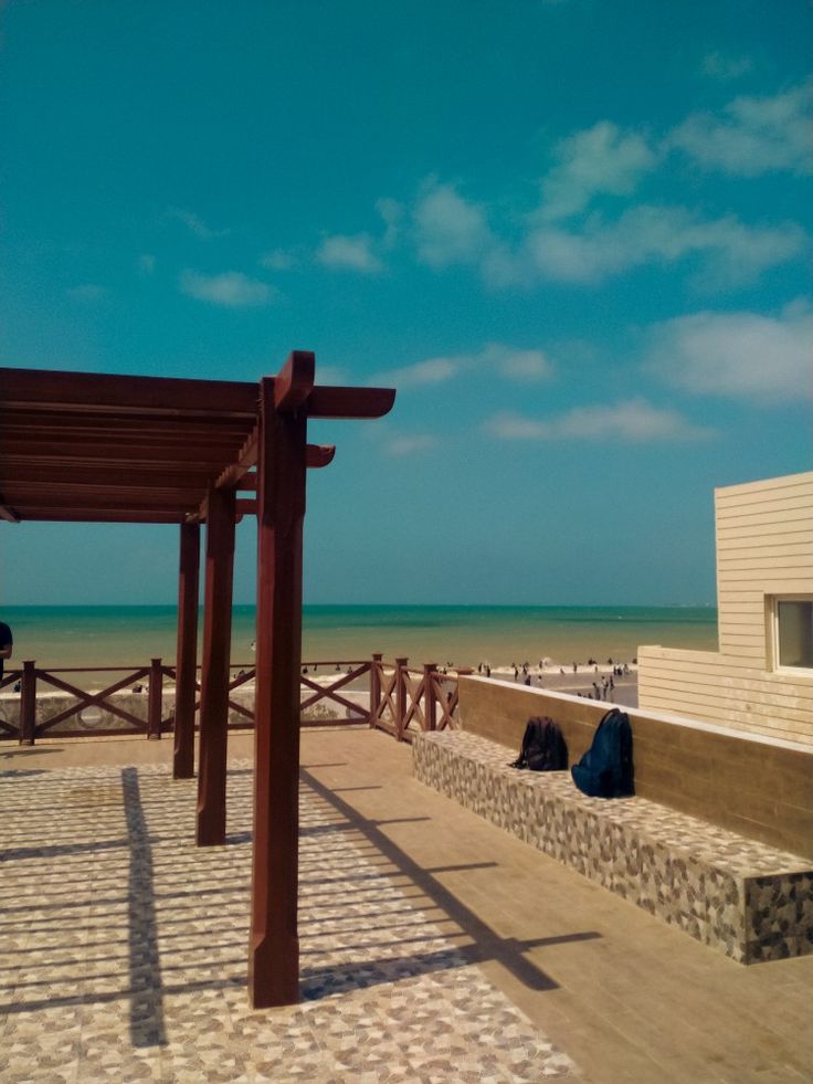 an empty beach area with benches and umbrellas