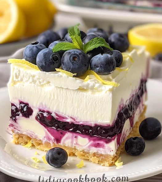 a piece of cake on a plate with blueberries and lemons