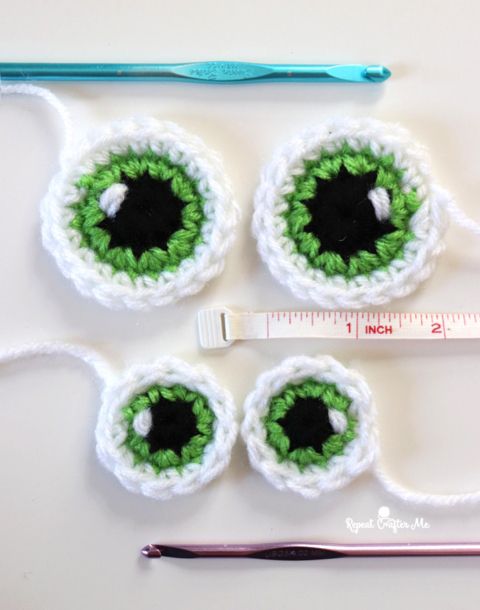 three crocheted green and white eyeballs are shown