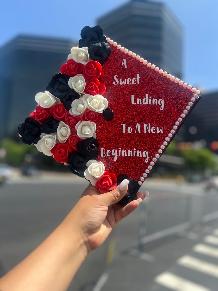 a hand holding up a red and white card with flowers on it that says sweet ending to a new beginning