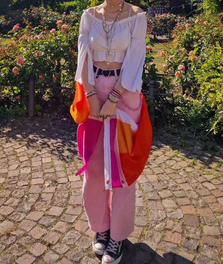 a woman in pink and orange outfit standing on cobblestone