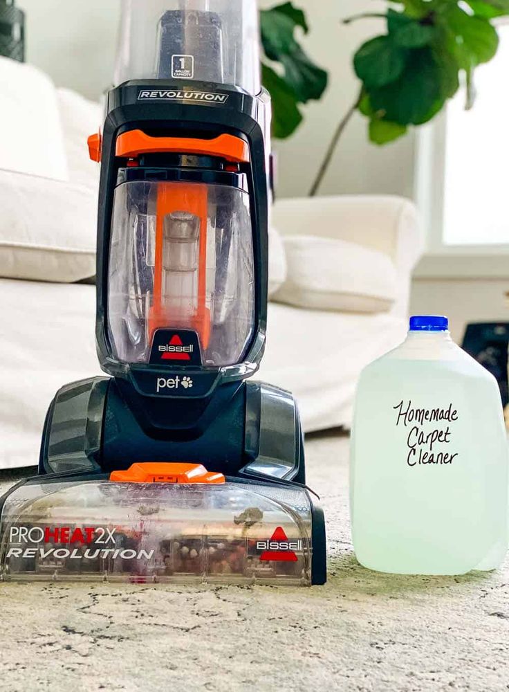 a close up of a vacuum on the ground near a gallon of water and a canister