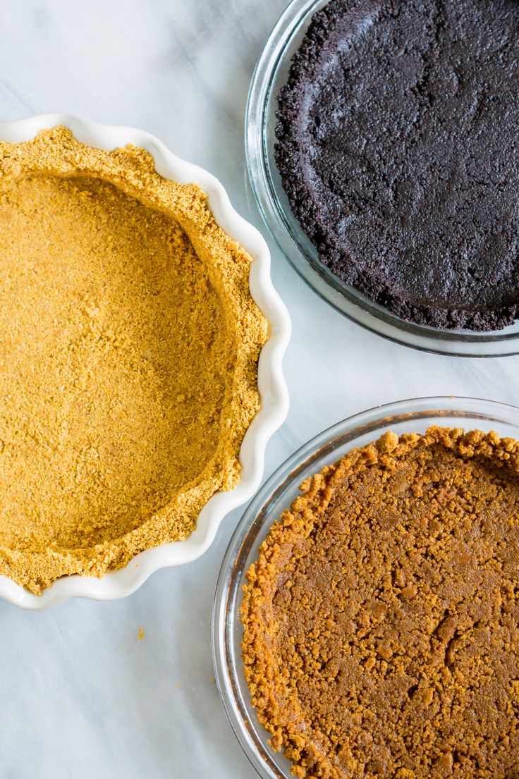 three pie pans filled with different types of pie toppings on top of a white counter