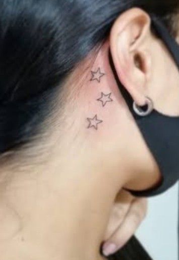 a woman's behind the ear has three stars on her left side and is wearing a black band