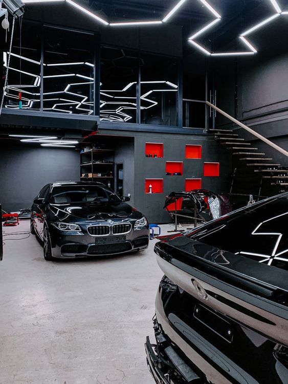 two cars parked in a garage with stairs leading up to the top floor and below them