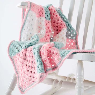 a crocheted blanket sitting on top of a white rocking chair