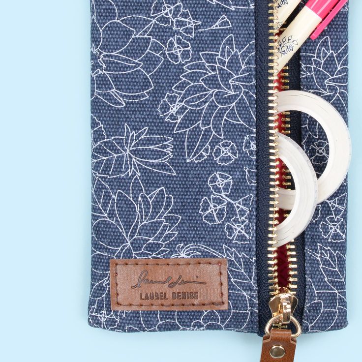 an open zippered pouch with various items in it on a blue and white background