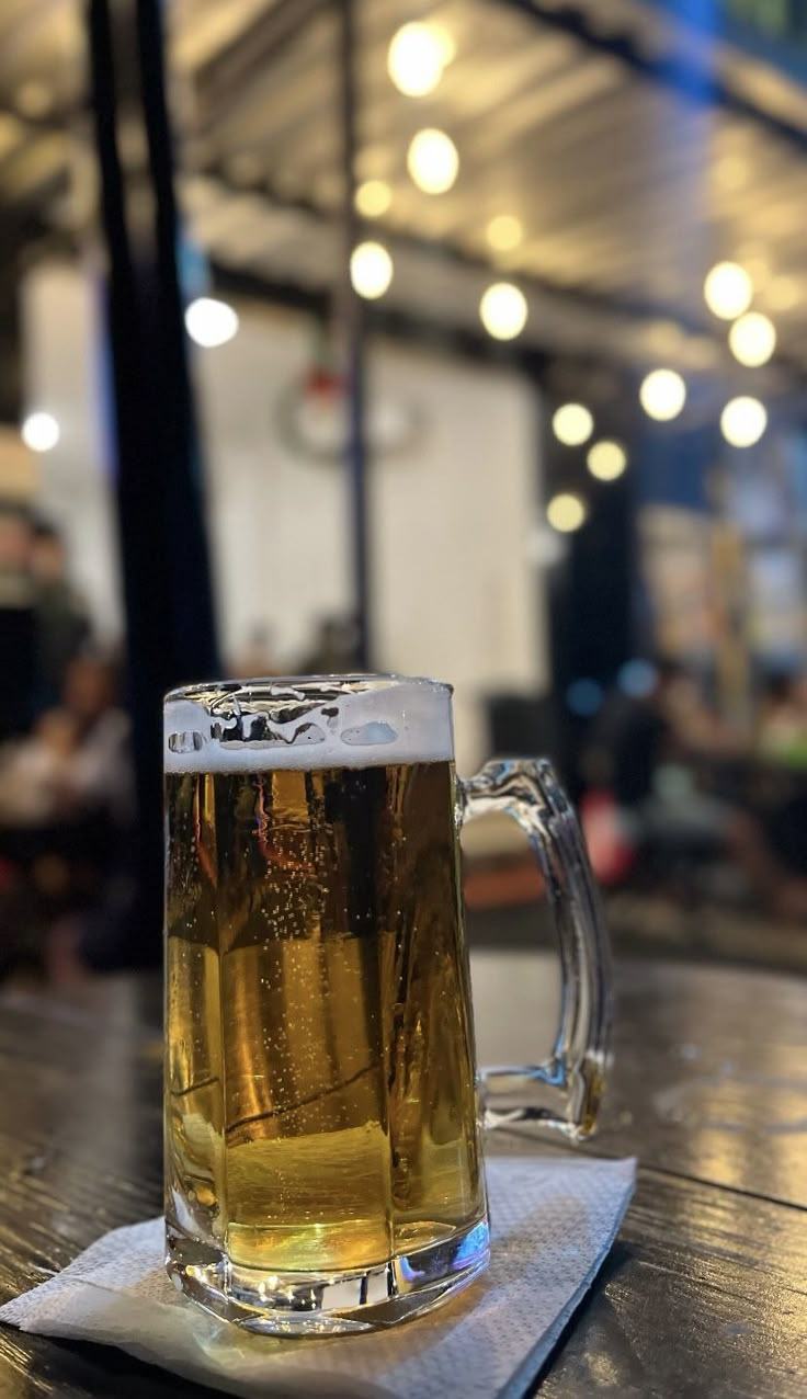 a mug of beer sitting on top of a wooden table