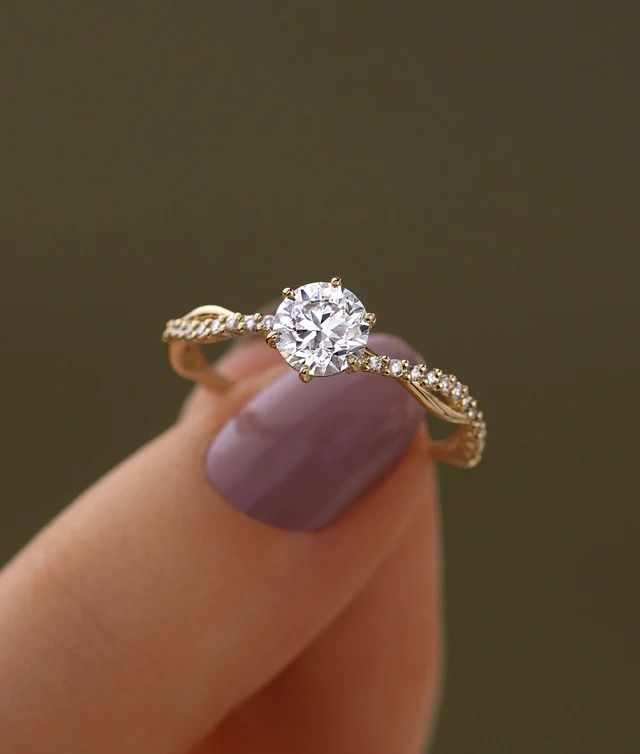 a woman's hand holding a ring with a diamond in the middle and a gold band around it