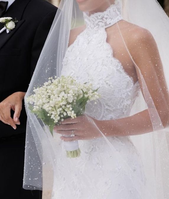 the bride and groom are standing together outside in their wedding day attire, dressed in black tuxedo with white flowers