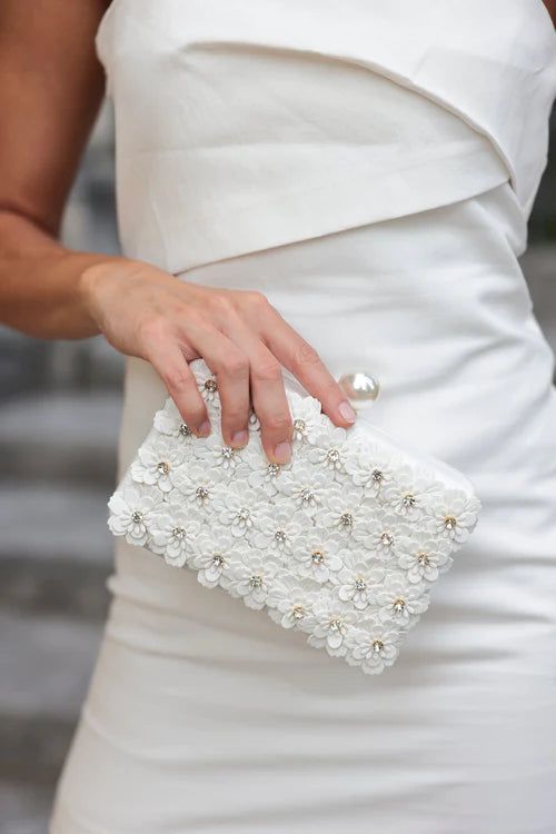 Fiorella Minaudiere Elevate your style with the Fiorella Minaudiere. This luxurious clutch is adorned with delicate flowers, sparkling rhinestones, and a classic faux pearl clasp. Its versatile design allows you to carry it as a clutch or use the detachable chain for a more effortless look. Perfect for any occasion, this elegant purse will be your go-to accessory. Glamorous Pearl Clutch For Formal Occasions, Glamorous Pearl Clutch For Formal Events, Elegant Pearl Evening Bag For Events, Formal Embellished Pearl Evening Bag, Elegant Pearl Evening Bag For Party, Pearl White Clutch With Pearl Embroidery For Formal Events, Elegant Pearl White Clutch With Pearl Embroidery, Formal Pearl White Clutch With Pearl Embroidery, Elegant Pearl Clutch For Events