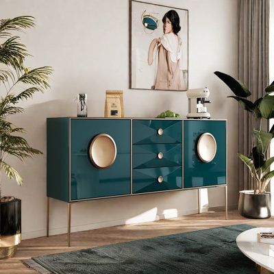 a living room scene with focus on the sideboard and plant in the foreground