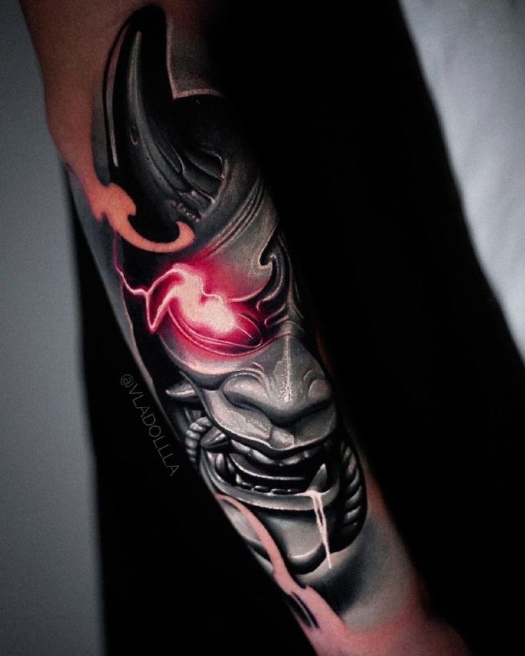 a man with a tattoo on his arm wearing a demon mask and red glowing eyes