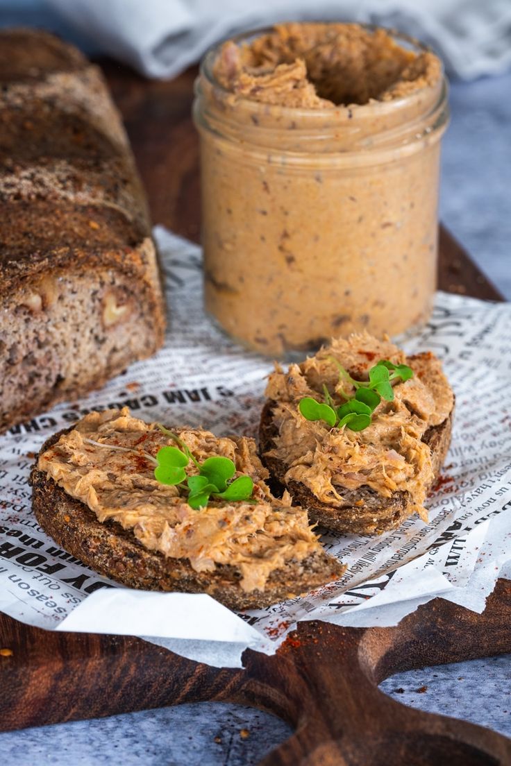 two pieces of bread sitting on top of a piece of paper next to a jar of peanut butter