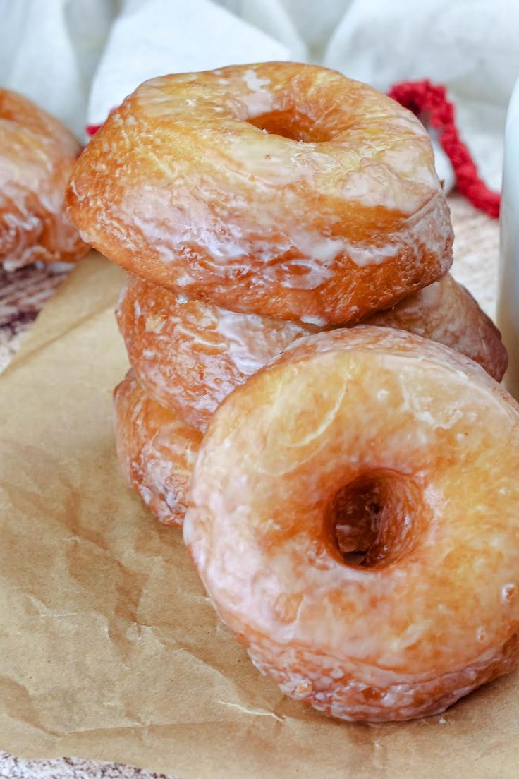 several glazed doughnuts are stacked on top of each other next to a glass of milk