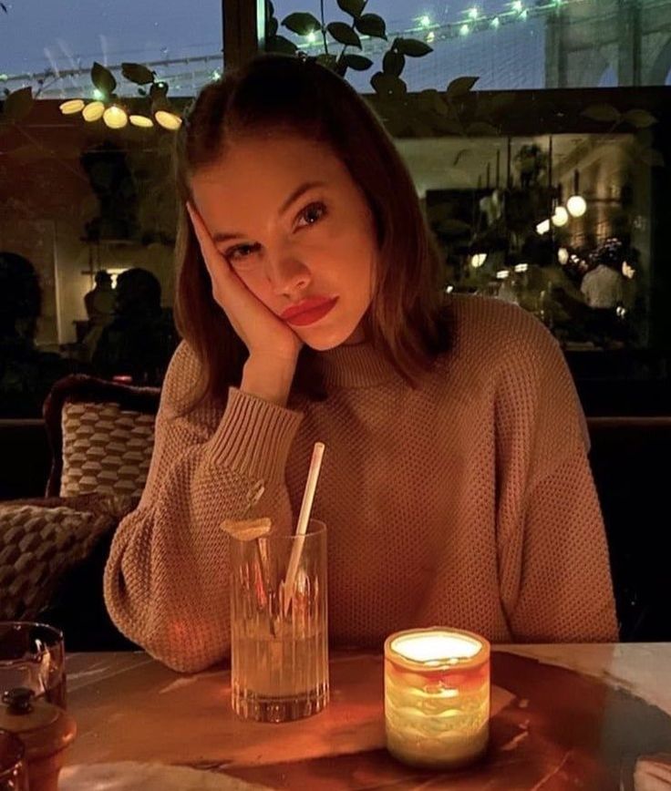 a woman sitting at a table with a candle in front of her and looking up