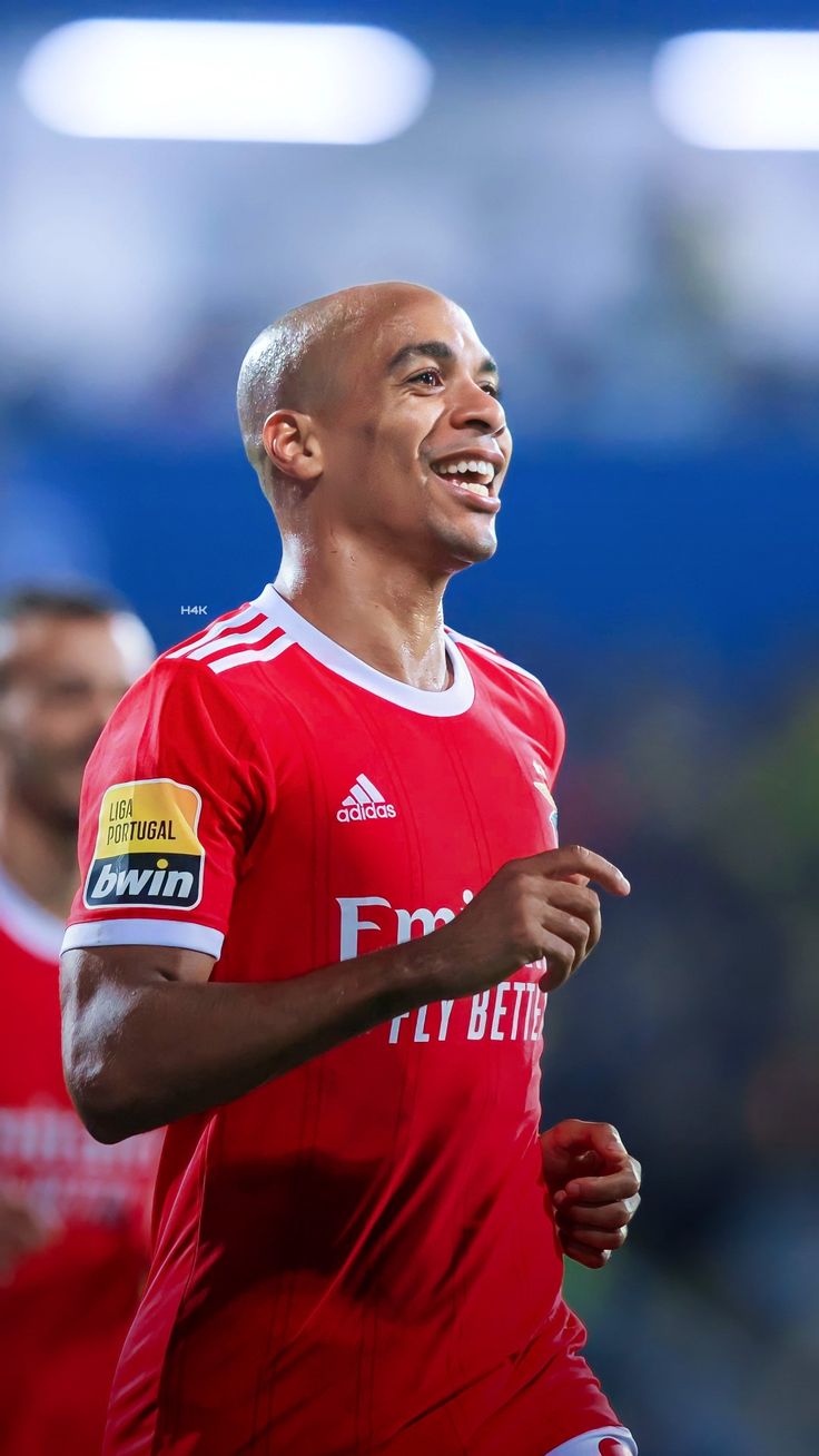 a man in a red jersey is smiling and looking to the side with his mouth open