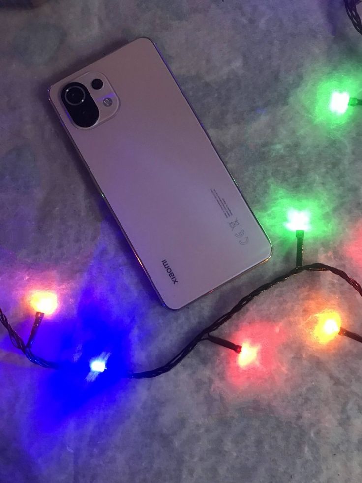 a cell phone laying on top of a table covered in colorful light stringing next to it's back cover