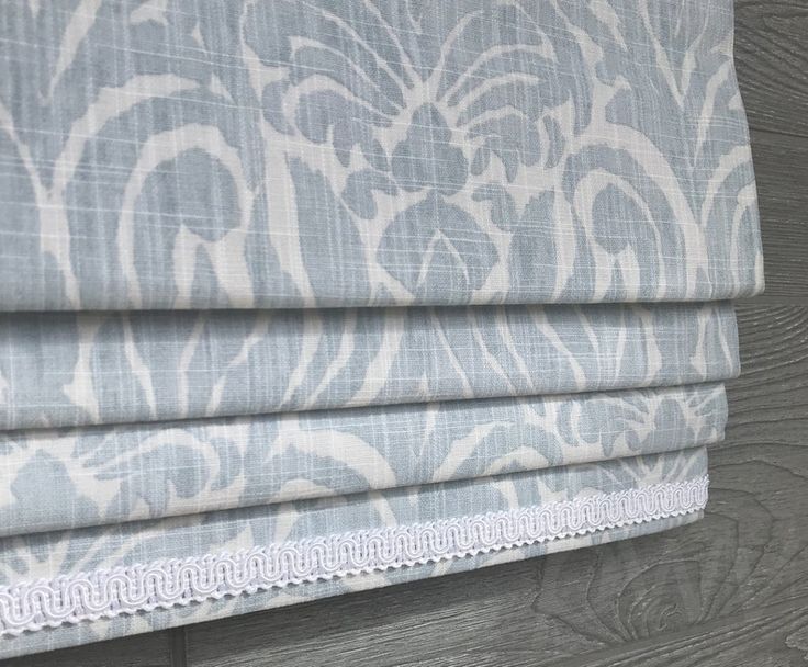 a close up view of a roman blind with blue and white damask pattern on it