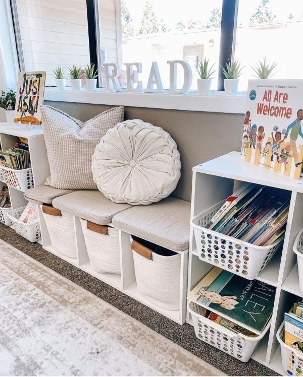 a room filled with lots of white baskets and bookshelves next to a window