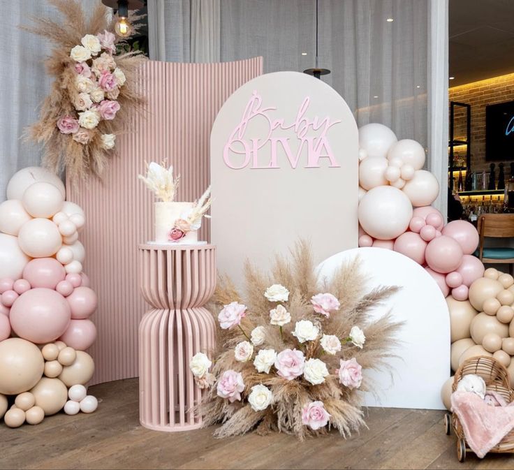 there are balloons and flowers on the table next to this cake stand for a baby shower