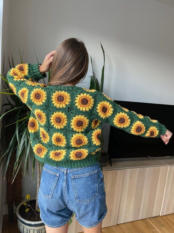 a woman standing in front of a tv wearing shorts and a sweater with sunflowers on it