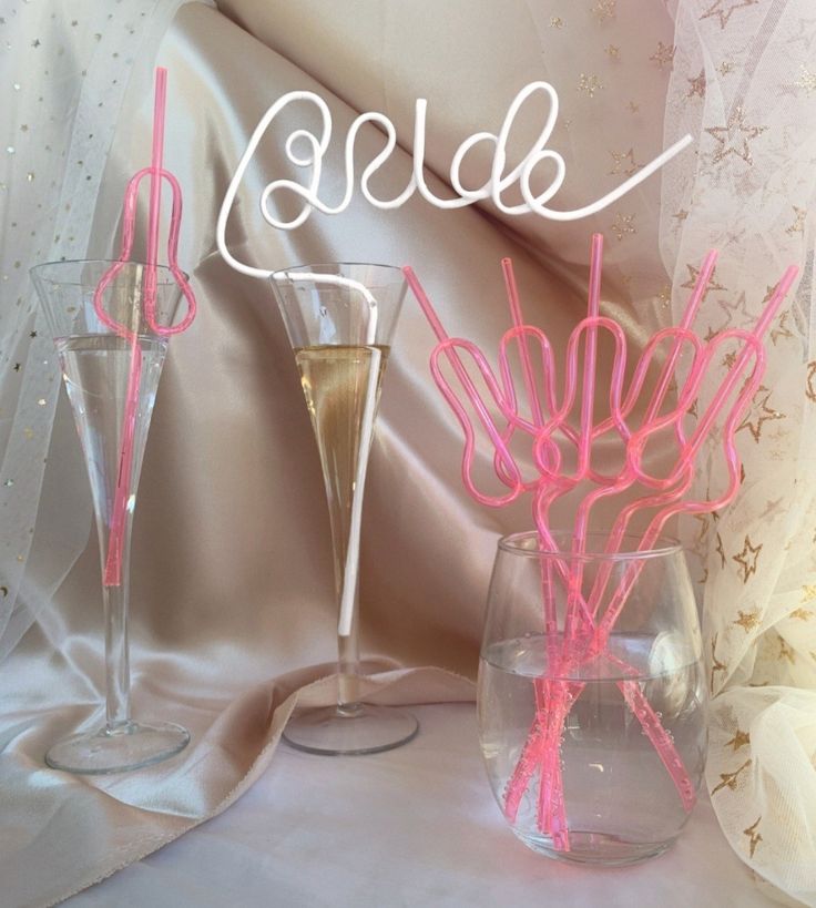 two vases filled with pink flowers next to each other on a white table cloth