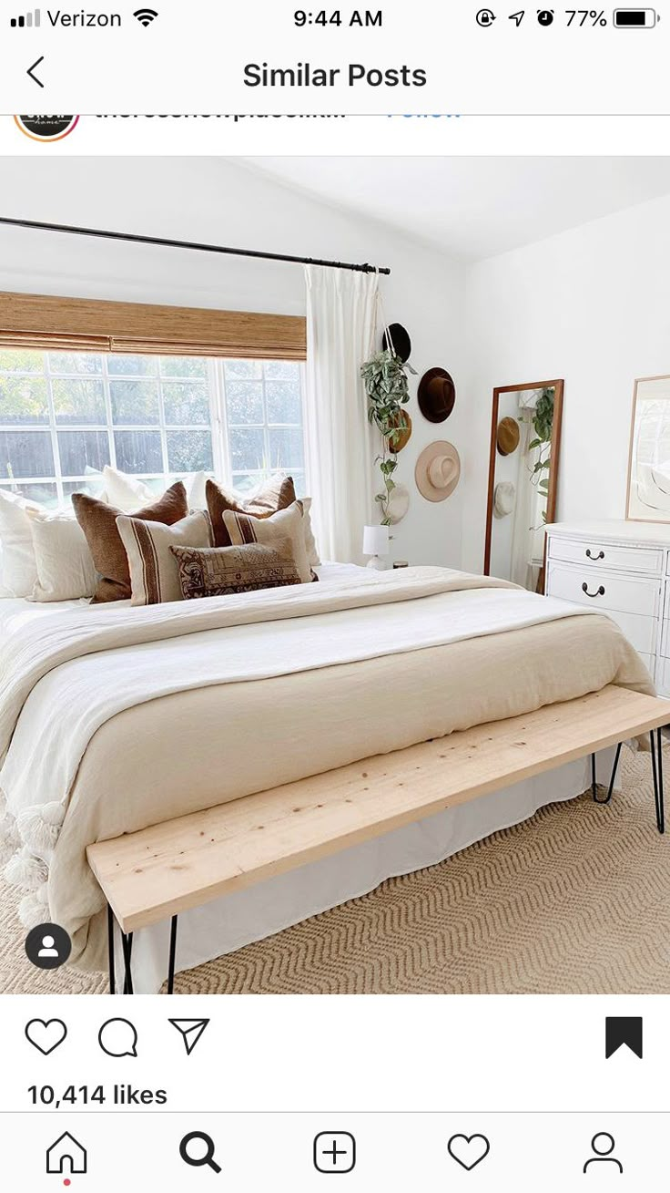 a white bed sitting next to a window with lots of pillows on top of it