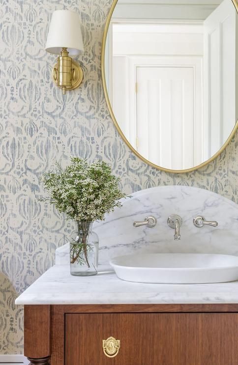 a bathroom sink with a mirror above it and a vase on the counter next to it