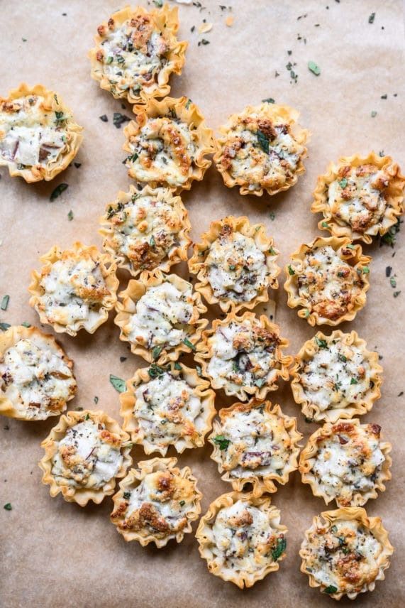 small appetizers with cheese and herbs are on a piece of parchment paper, ready to be eaten