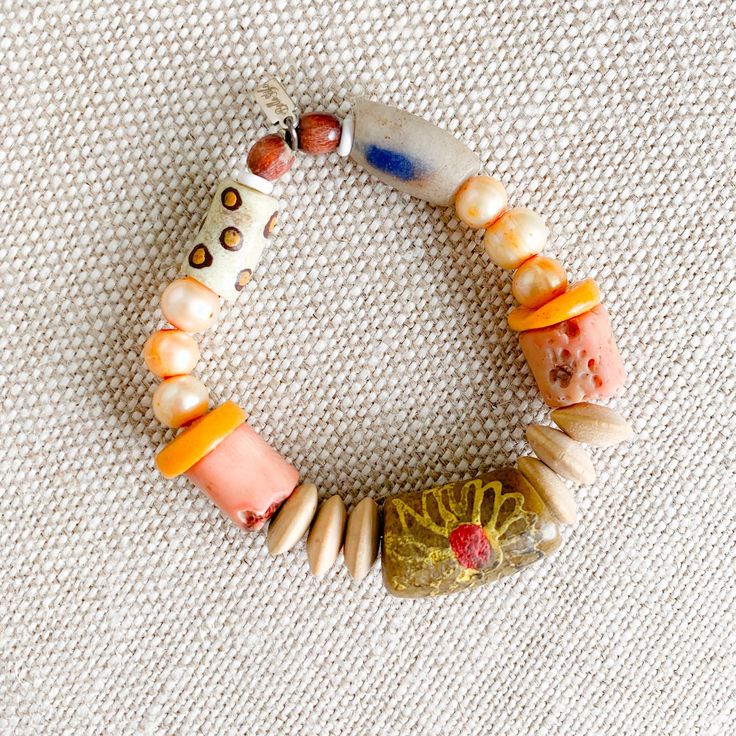 Peach, yellow, and neutral colored sustainable bead bracelet. African prayer bead in Light Tan, peach coral, rosewood, and peach freshwater pearls. Measures 7-8”, size regular (M-L) Sterling silver BelleStyle logo tag. Prayer bead symbolize health, love, good fortune and loyalty. One of a kind. Comes in linen travel pouch. Made in USA. Apricot Beaded Round Bead Jewelry, Handmade Orange Beaded Bracelets For Meditation, Handmade Peach Bracelets With Round Beads, Peach Colored Jewelry With Colorful Round Beads, Artisan Orange Bracelet With Colorful Beads, Artisan Orange Bracelets With Colorful Beads, Artisan Orange Hand-strung Beaded Bracelets, Bohemian Peach Bracelets For Gifts, Bohemian Peach Bracelets For Gift